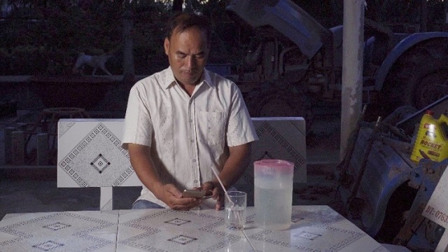 Người nông dân kiểm tra ứng dụng AWD trên điện thoại tại nhà